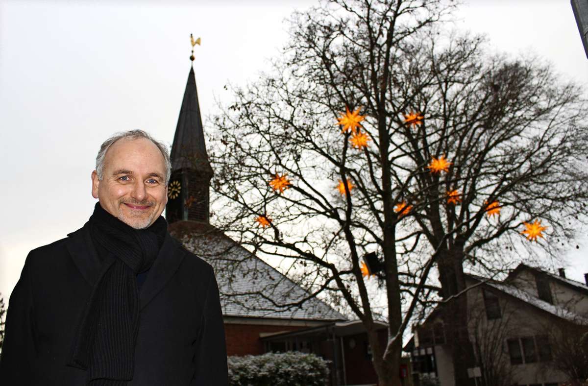 Veit Mathauer, der Vorsitzende des Bürgervereins Schönberg, vor einer Reihe leuchtender Stern vor der Himmelfahrtskirche Foto: /Caroline Holowiecki