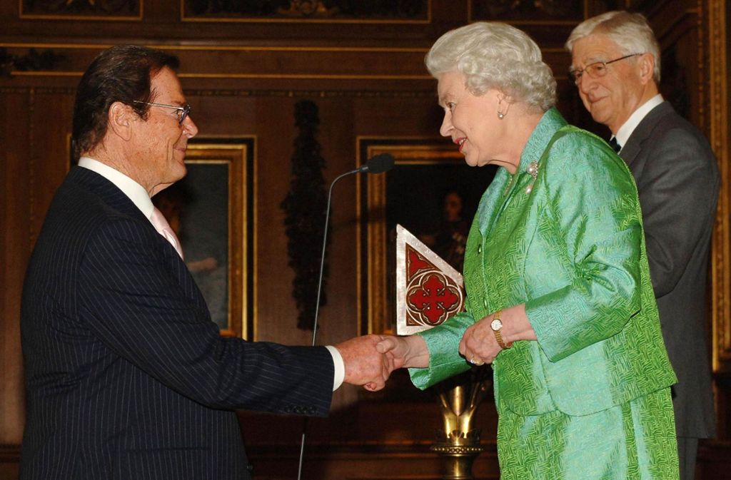 Roger Moore (links) gibt am 03. Mai 2006 Königin Elisabeth II. von England die Hand während eines Empfangs im Schloss von Windsor.