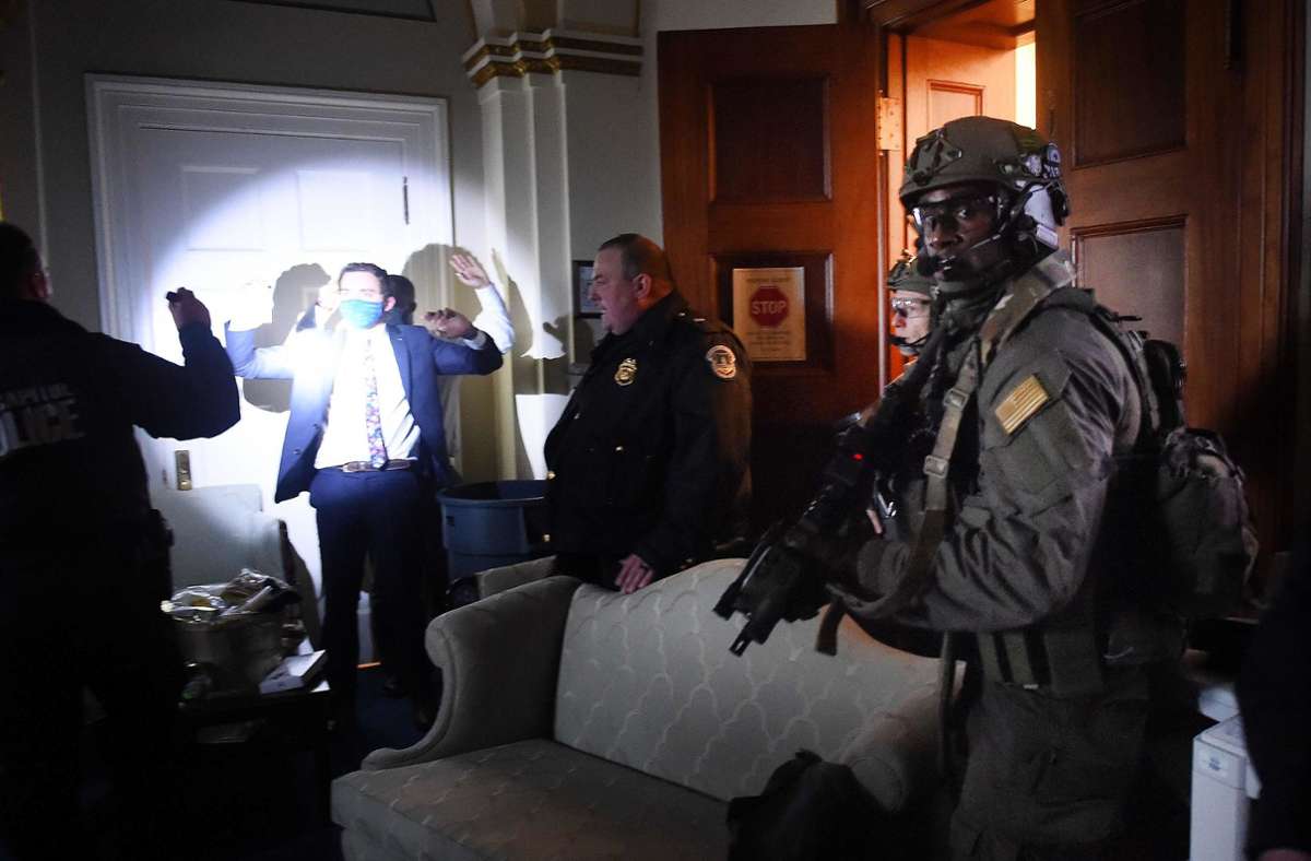 Ein Kongressmitarbeiter hält seine Hände hoch, während ein Sondereinsatzkommando jede Person im Raum überprüft.