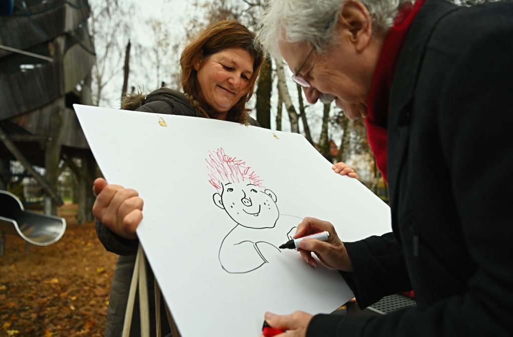 Die Kinderpflegerin Angela Göppner hält ein Plakat in den Händen, auf das Kinderbuchautor Paul Maar ein Sams zeichnet.
