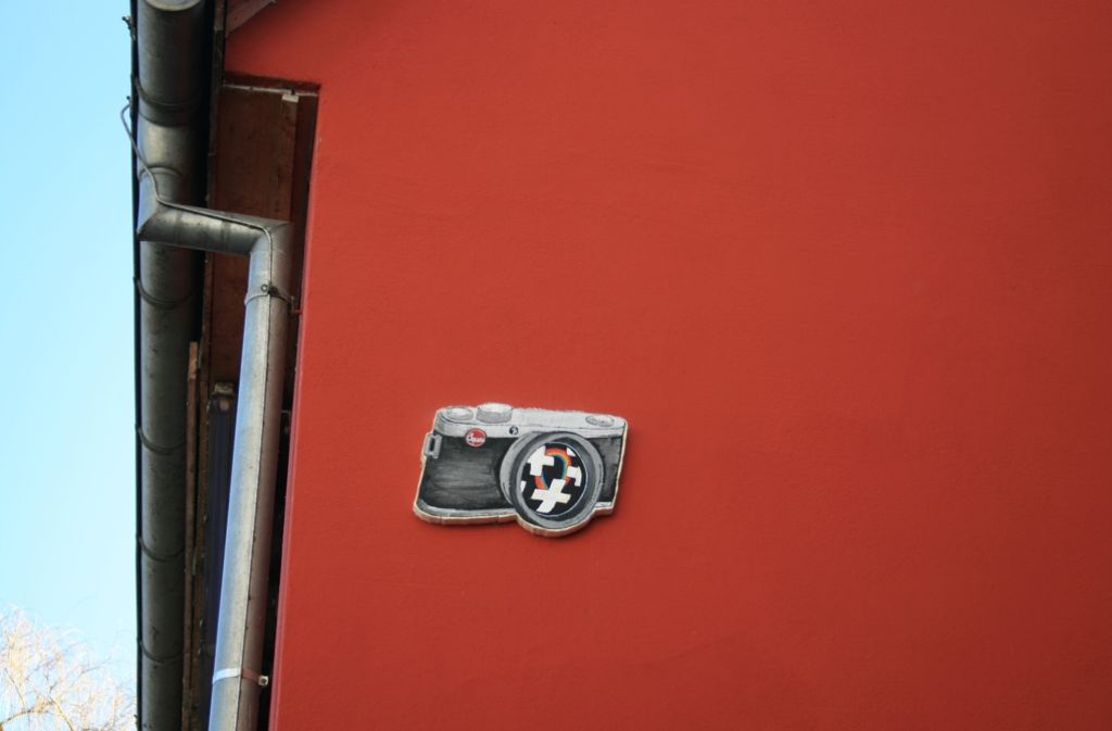 Leica-Kamera aus bemaltem und ausgeschnittenen Styropor an einer Hauswand.