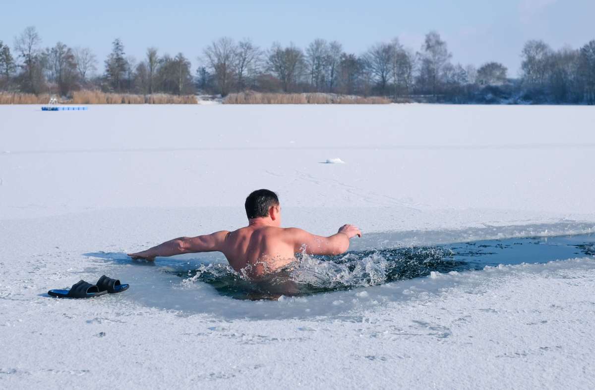 Im Alb-Donau-Kreis genießt Winterschwimmer Niko ein Eisbad im zugefrorenen Baggersee.