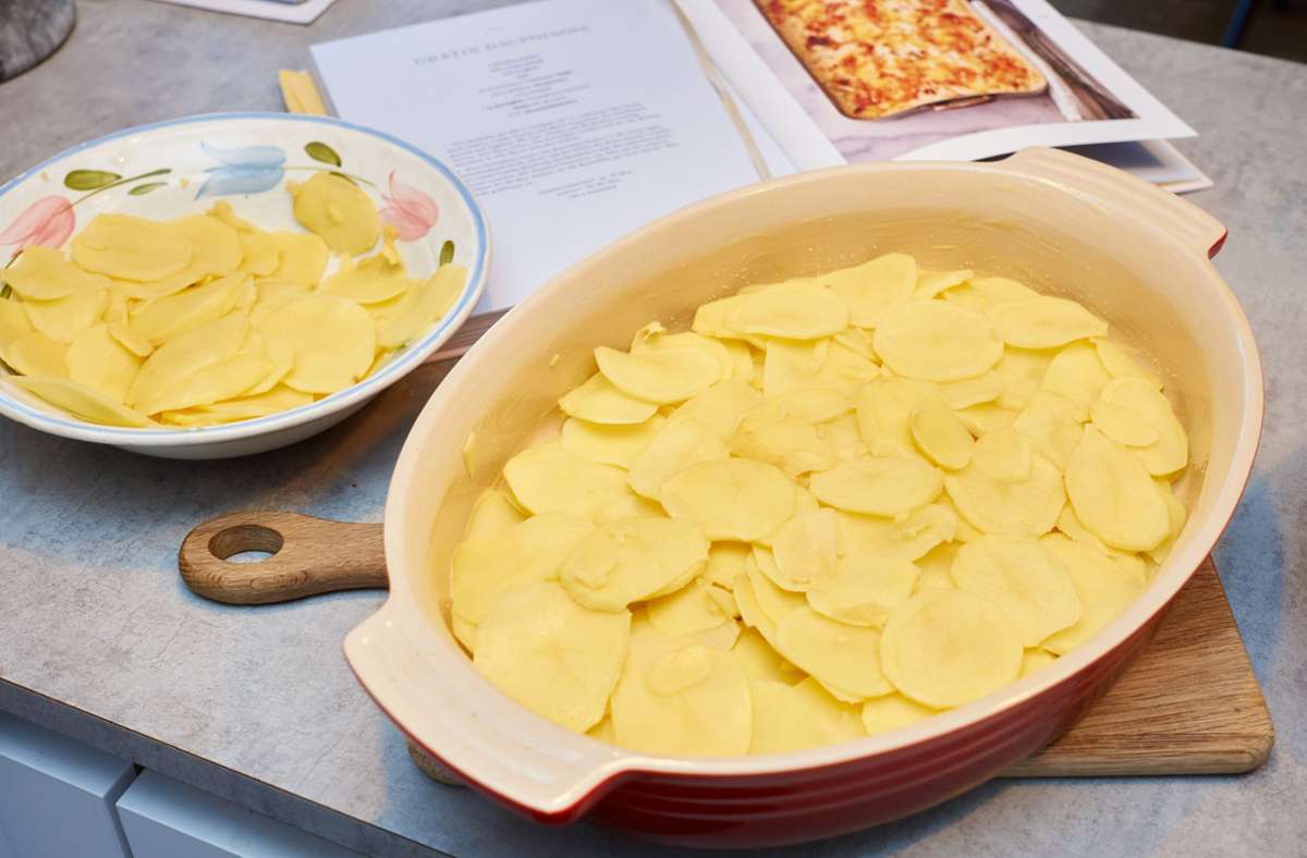 Eine Gratinform fetten. Die Kartoffelscheiben in die Form legen, zwischendurch leicht salzen und die Hälfte des Käses darauf verteilen.