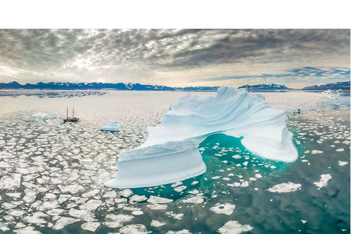 Ein Segelschiff in den Weiten des teilweise von Eis bedeckten Scoresbysunds im Osten Grönlands.