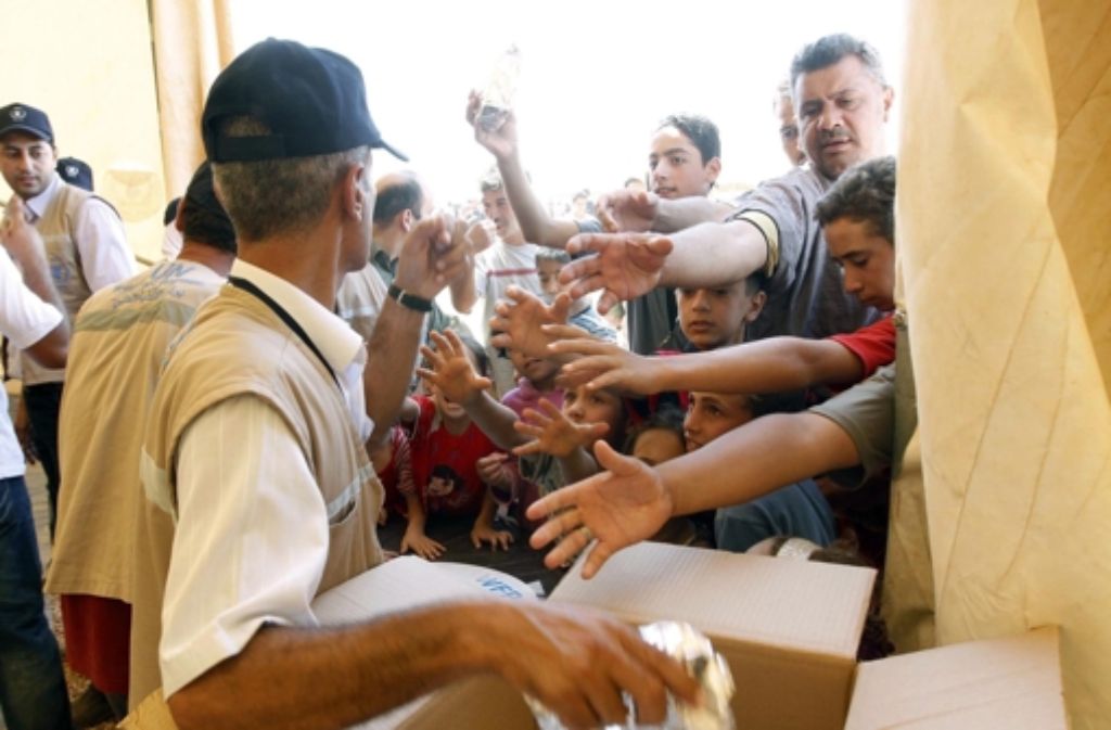 Jede Mahlzeit wird sehnsüchtig erwartet: Mitarbeiter des UN-Flüchtlingshilfswerks UNHCR verteilen im jordanischen Flüchtlingslager in Mafraq Lebensmittel an die Syrer. Foto: EPA