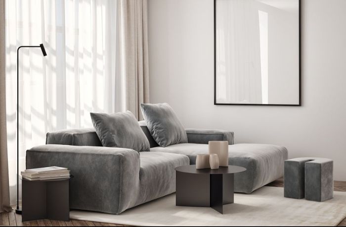 Sofa, Couchtisch und Sitzpouf werden auf dem Teppich platziert, der eine gemütliche Sitzecke schafft.