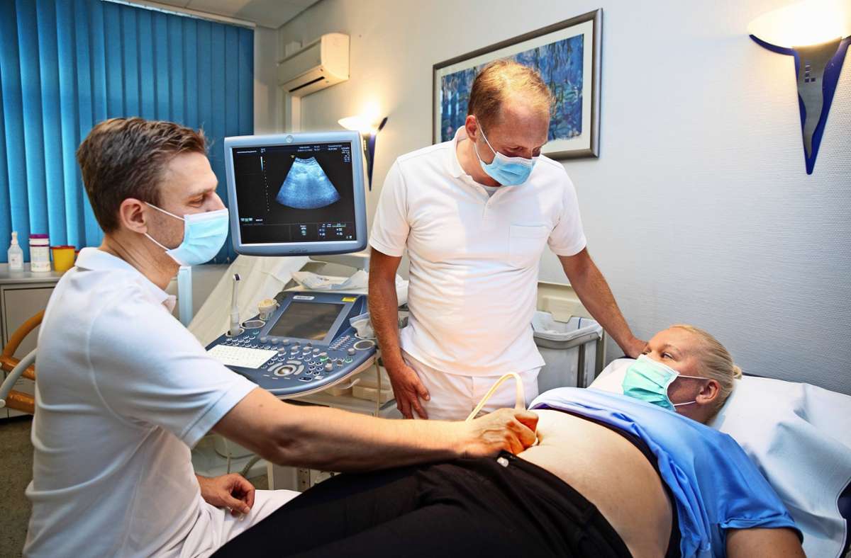 Stefan P. Renner macht eine Ultraschalluntersuchung des Beckenraumes von Ivonne van der Lee, während Michael Burkhardt mit der Patientin spricht.