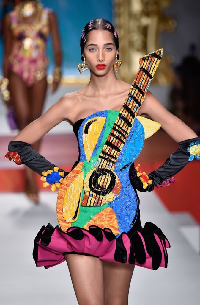 Denn das italienische Modelabel setzt für 2020 nicht nur auf kräftige und knallige Farben, sondern auch auf skurrile Formen. Da sind Gitarren-Kleider dabei ...