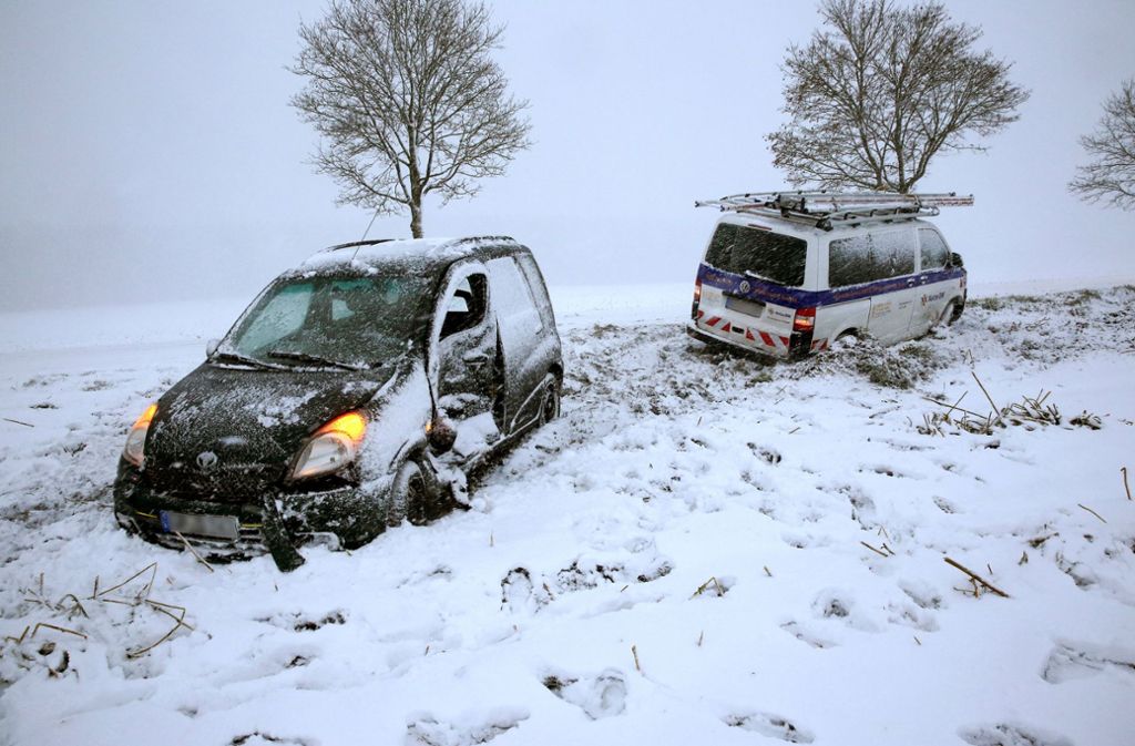 Riedlingen-Zell: Zwei beschädigte Fahrzeuge stehen bei starkem Schneefall neben einer Straße, nach dem sie auf schneeglatter Fahrbahn kollidiert sind. Eine Person wurde verletzt.