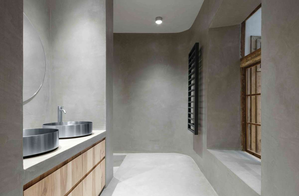 Hier wird strenge Schlichtheit gefeiert: Blick in ein Badezimmer mit Wachszementspachtelung. Das Material versiegelt die Wände fugenlos und macht sie wasserunempfindlich. Das Apartment befindet sich in Brixen, Südtirol. Gestaltet wurde es von Architekt Daniel Ellecosta.