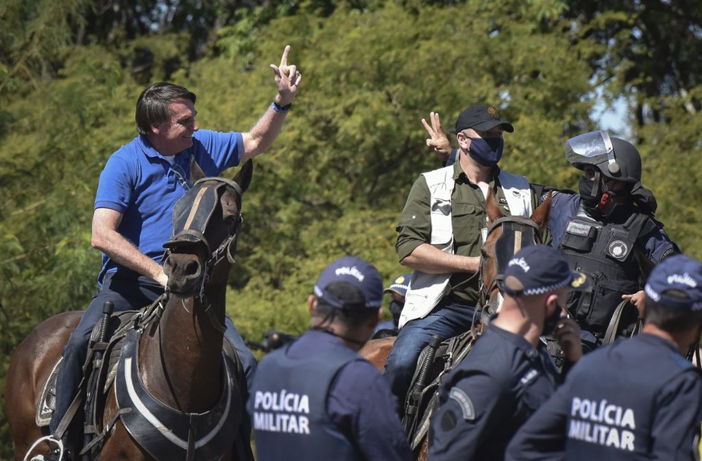 Jair Bolsonaro (l), Präsident von Brasilien, reitet auf einem Pferd und begrüßt seine Anhänger vor dem Präsidentenpalast.