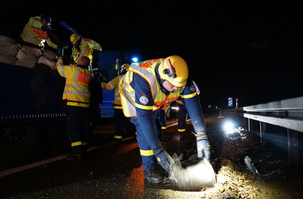 Mit Sandsäcken sichern Feuerwehrleute bei Gruibingen die Autobahn A8. Foto: SDMG