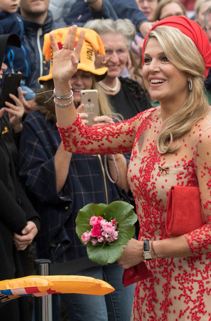 Ankunft 2018 in Trier: Königin Máxima der Niederlande winkt an der Porta Nigra. Sie ist nicht zu übersehen in ihrem Designerkleid. Schuhe sowie Handtasche im passenden Rotton ergänzen das Outfit. Ein Hingucker: der turbanartige Hut.