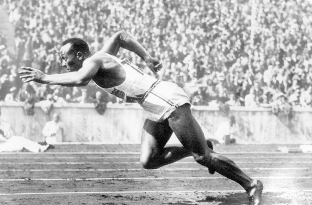 Die Nationalsozialisten benutzten die Winterspiele 1936 in Garmisch-Partenkirchen und die Sommerspiele 1936 in Berlin als Propagandaforum, um das Ansehen Deutschlands zu verbessern und Friedensbereitschaft vorzutäuschen. Der US-amerikanische Leichtathlet Jesse Owens (im Bild) beim Start zum 200-Meter-Lauf in Berlin. Er gewann die Goldmedaille über 100 Meter, 200 Meter, 4 xl 100 Meter und im Weitsprung. Mit seinen Siegen wurde er – sehr zum Unmut der Nazis – zum sportlichen Symbol der Spiele.