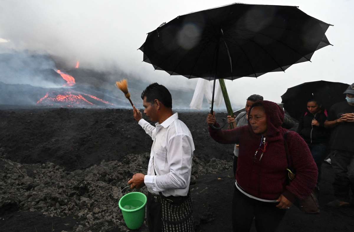 Ein Mann spritzt mit Wasser in Richtung des Vulkans. Die Menschen hoffen auf ein Ende der enormen Aktivität.