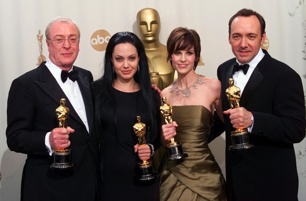Nein, die zweite von Links ist nicht Morticia Addams von der Addams-Family, sondern die damals noch blutjunge Angelina Jolie bei der Oscar-Verleihung 2000. Rechts neben ihr in Schlamm-Gold: die Schauspielerin Hilary Swank und der Schauspieler Kevin Spacey. Links außen: der Schauspieler Michael Caine.