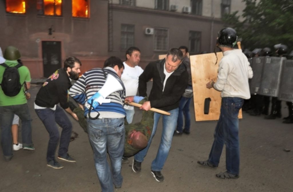 Helfer versuchen in der Nähe des brennenden Gewerkschaftshauses in Odessa einen verletzten prorussischen Demonstranten in Sicherheit zu bringen.