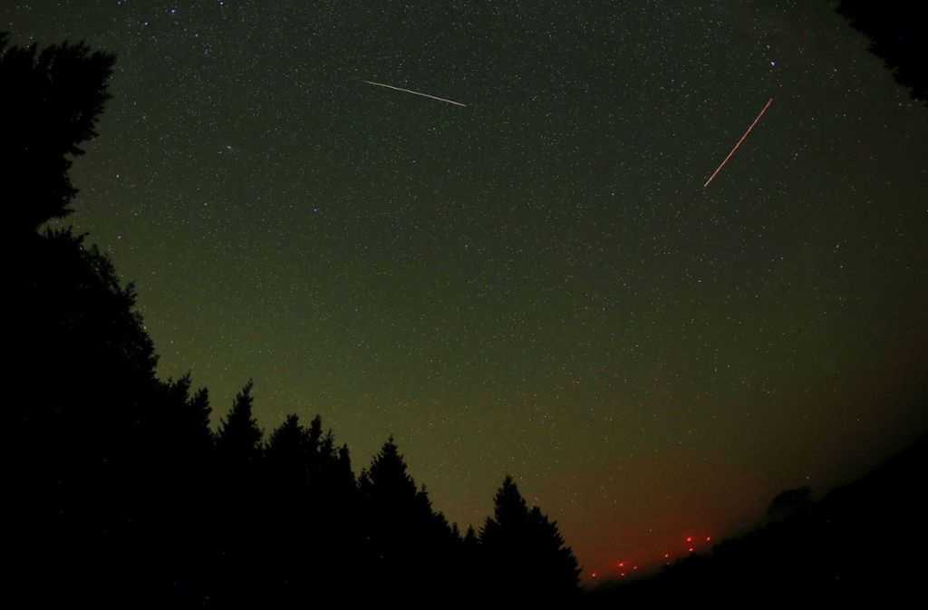 Eine Sternschnuppe (links) ist in der Nähe vom Gemünd (Nordrhein-Westfalen) in der Eifel am Himmel neben der Leuchtspur eines Flugzeuges (rechts) zu sehen.