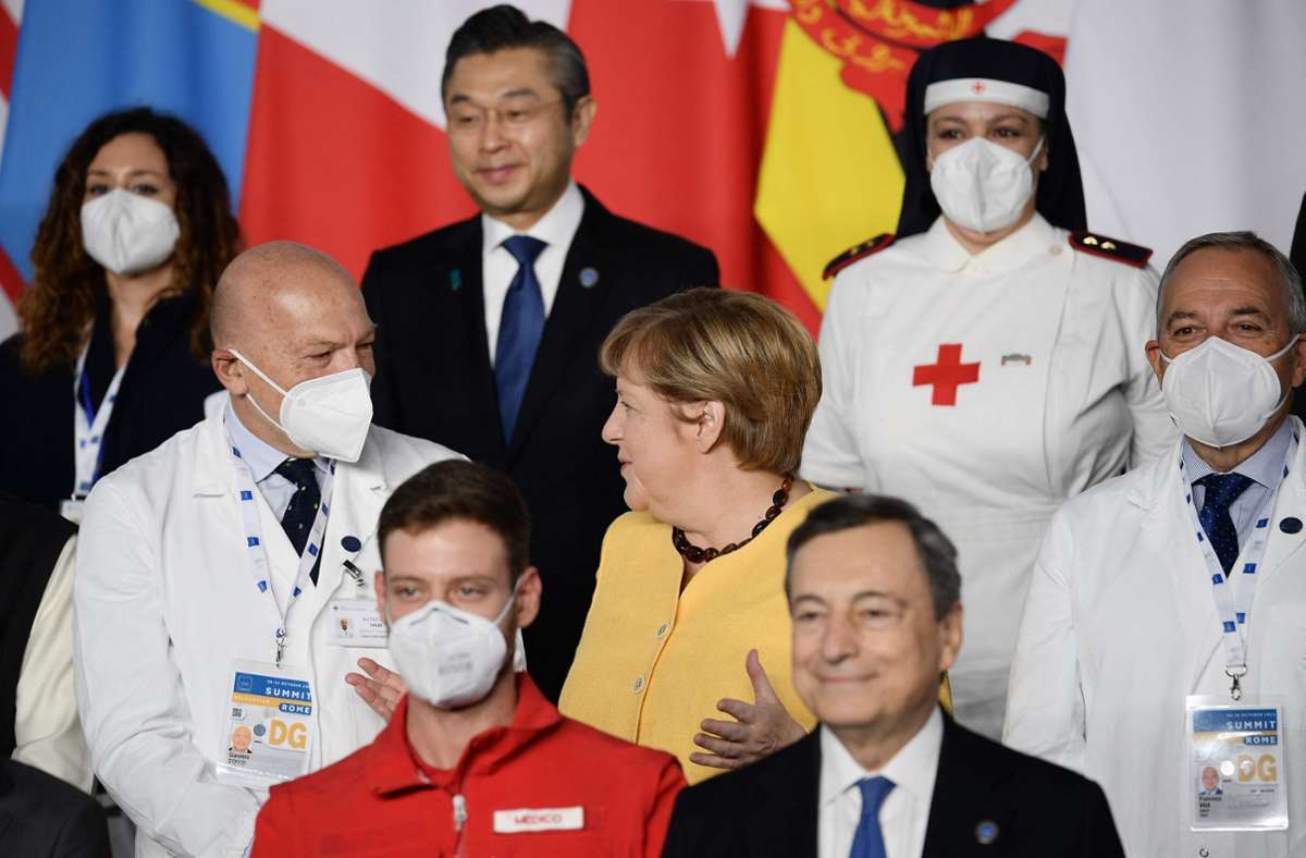 Bundeskanzlerin Merkel im Gespräch mit einem Mitarbeiter des italienischen Gesundheitswesen. Foto: AFP/FILIPPO MONTEFORTE