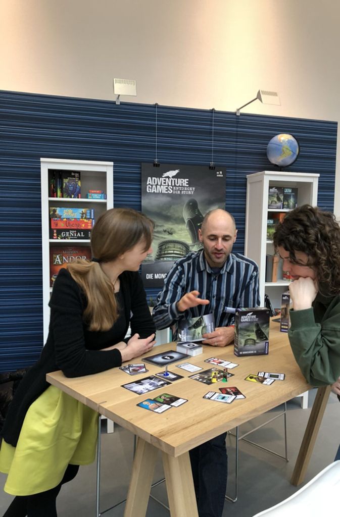 Auch Erwachsene rätseln gern: Kosmos-Spieleredakteur Michael Sieber-Baskal erklärt seinen Kolleginnen die Regeln für das neue Abenteuer-Spiel des Verlags.