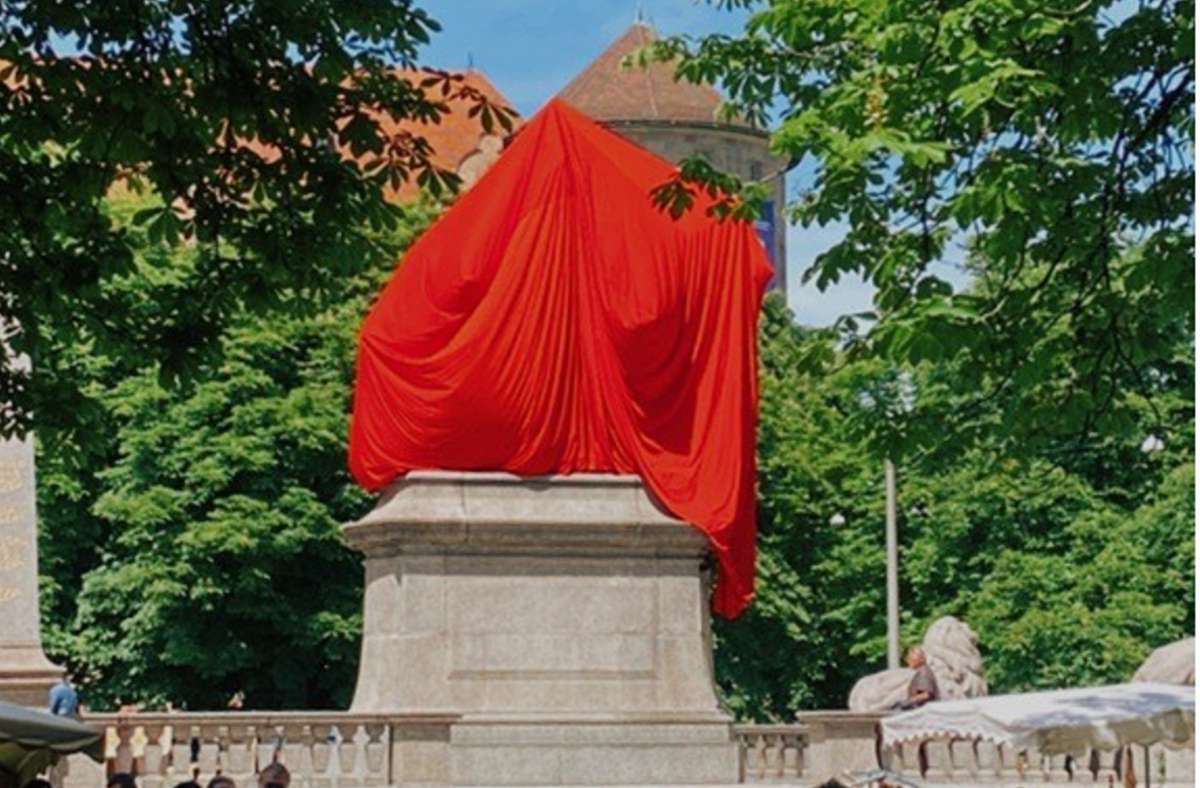 Das Denkmal auf dem Karlsplatz ist mit einem roten Tuch verhüllt worden. Foto: Carina Kriebernig
