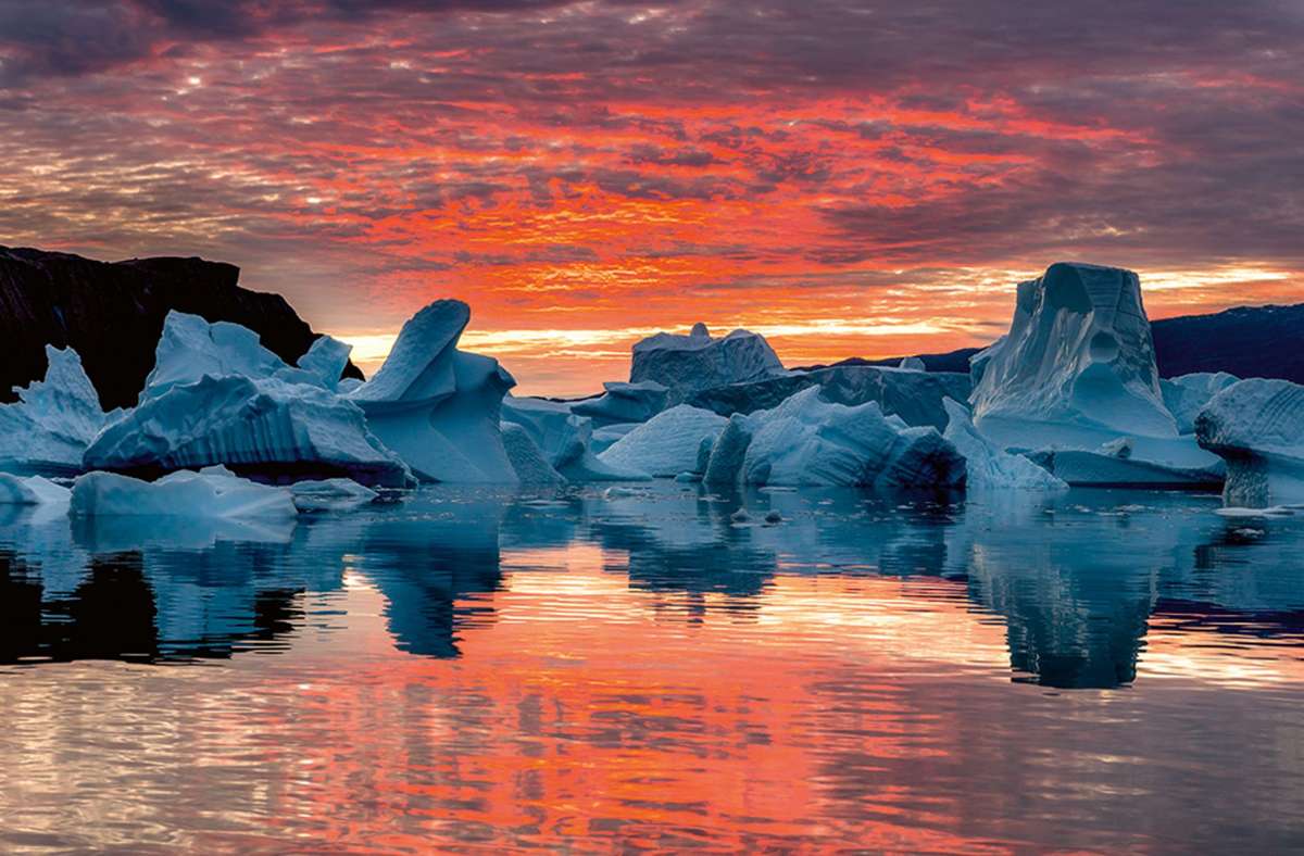 Fotografiert vom Zodiac aus, dem für Polarreisen unentbehrlichen Schlauchboot mit festem Rumpf: Eisberge bei Sonnenaufgang am Scoresbysund, dem größten Fjordsystem der Welt, im Osten Grönlands.