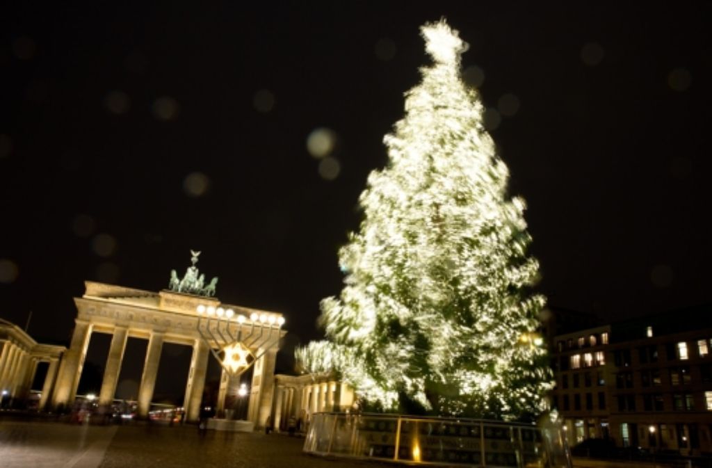 Der hell erleuchtete Weihnachtsbaum auf dem Pariser Platz vor dem Brandenburger Tor bewegt sich im Wind in Berlin.