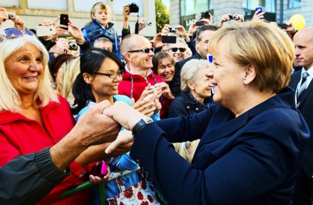 Nach dem Gottesdienst schüttelt Bundeskanzlerin Angela Merkel die Hände von Bürgern, die sich vor dem Hauptportal des Gotteshauses versammelt haben und sich über die Begegnung mit ihr sichtlich freuen.