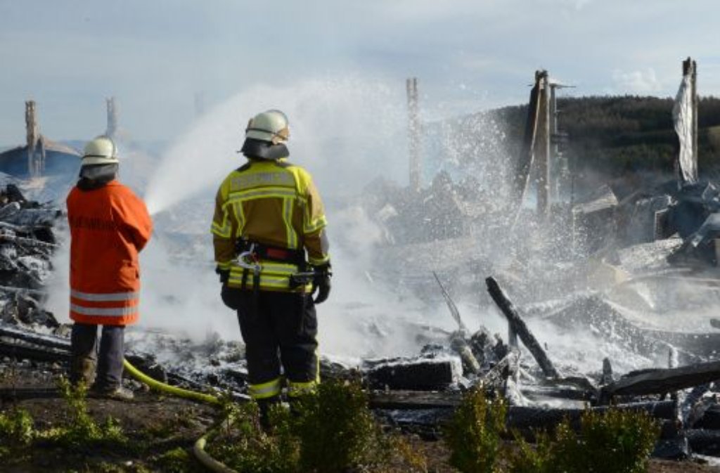 Ein Feuerwehrmann löscht den abgebrannten Kamelhof.